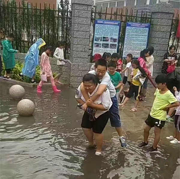 聊城：大雨过后校门口积水，95年女校车管理员背38个孩子上校车