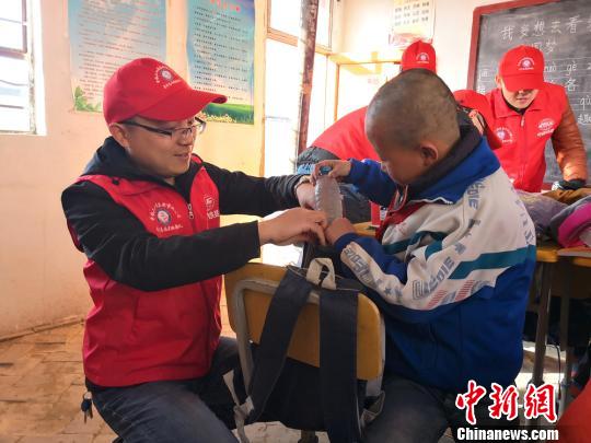 樊恒东(左)给甘肃榆中县北山的魏家台教学点小学生送学习用品。 许岗 摄