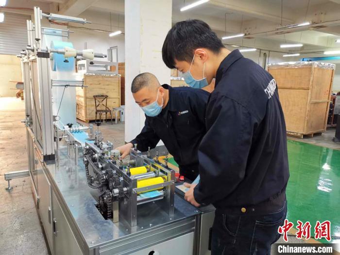 资料图：技术工人在对口罩机生产线进行最后调试。 姜辉 摄